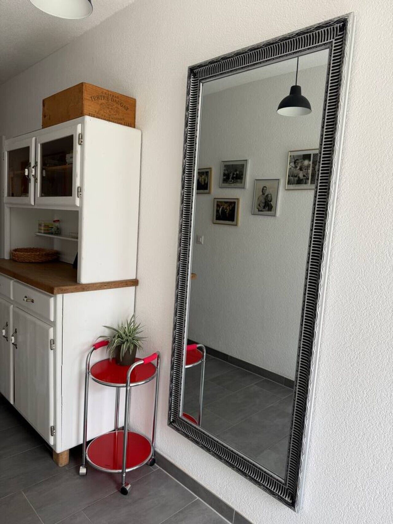 Ein Zimmer mit einem weißen Schrank, einem Spiegel und einem roten Sessel.