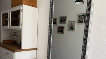 Ein Zimmer mit einem weißen Schrank, einem Spiegel und einem roten Sessel.