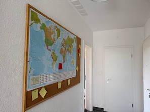 A room with a large world map on the wall, a door, and a bulletin board with notes. - Spacious apartment with a private garden and entrance (Huttwil)