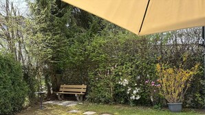 A garden with a bench, stepping stones, and a potted plant. - Spacious apartment with a private garden and entrance (Huttwil)