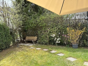 Ein Garten mit einer Bank, einem Kiesweg und einem Blumentopf.