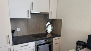 A compact kitchen with a built-in oven, a microwave, and a sink. - Spacious apartment with a private garden and entrance (Huttwil)