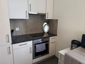 Eine kleine Küche mit Backofen, Mikrowelle und Spüle.