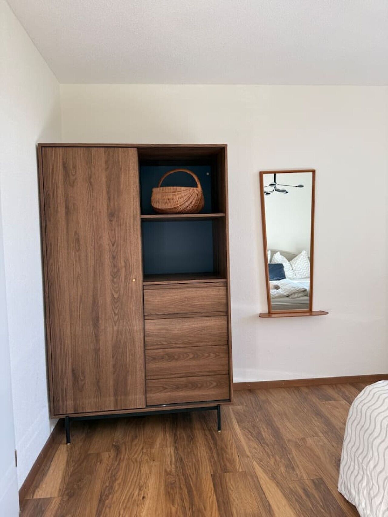 Ein Holzschrank mit Spiegel und Korb.