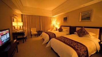 A hotel room with two beds, a desk, a chair, a television, and a large window.