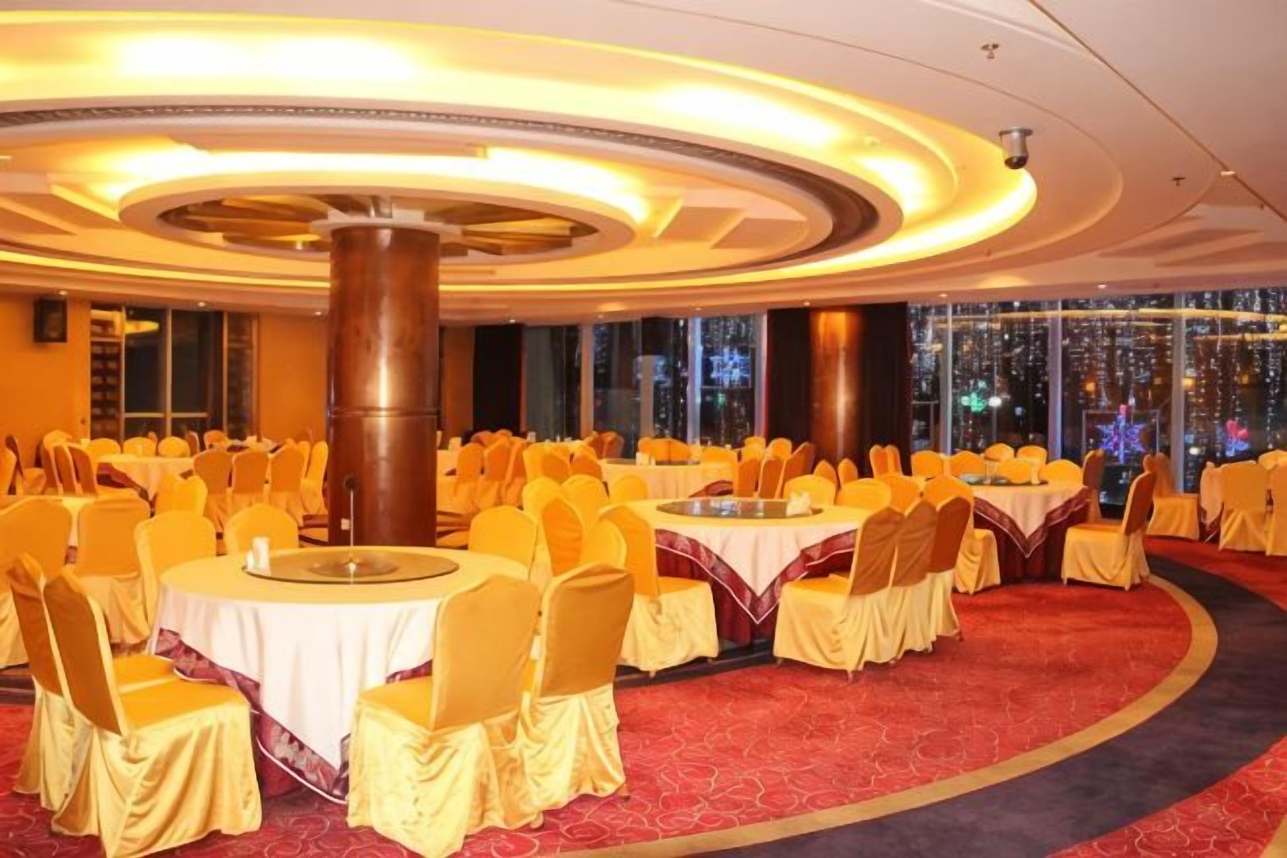 A banquet hall with round tables, chairs, and a red carpet.