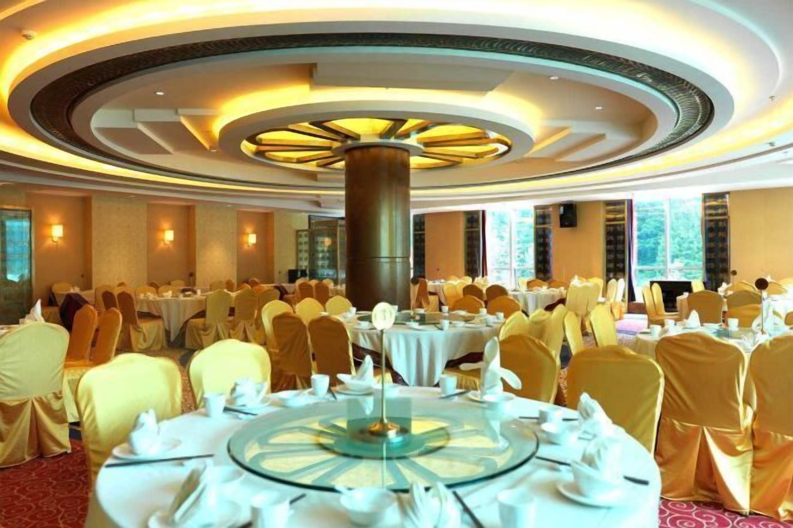 A banquet hall with round tables, chairs, and a central decorative column.