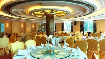 A banquet hall with round tables, chairs, and a central decorative column.