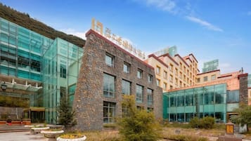 A modern building with a glass facade, stone accents, and a courtyard with planters.