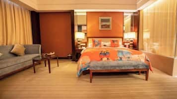 A hotel room with a bed, a sofa, a small table, and a window with curtains.