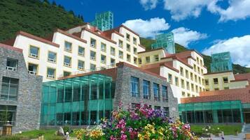 A multi-story hotel with a modern glass facade, surrounded by a landscaped garden with colorful flowers.