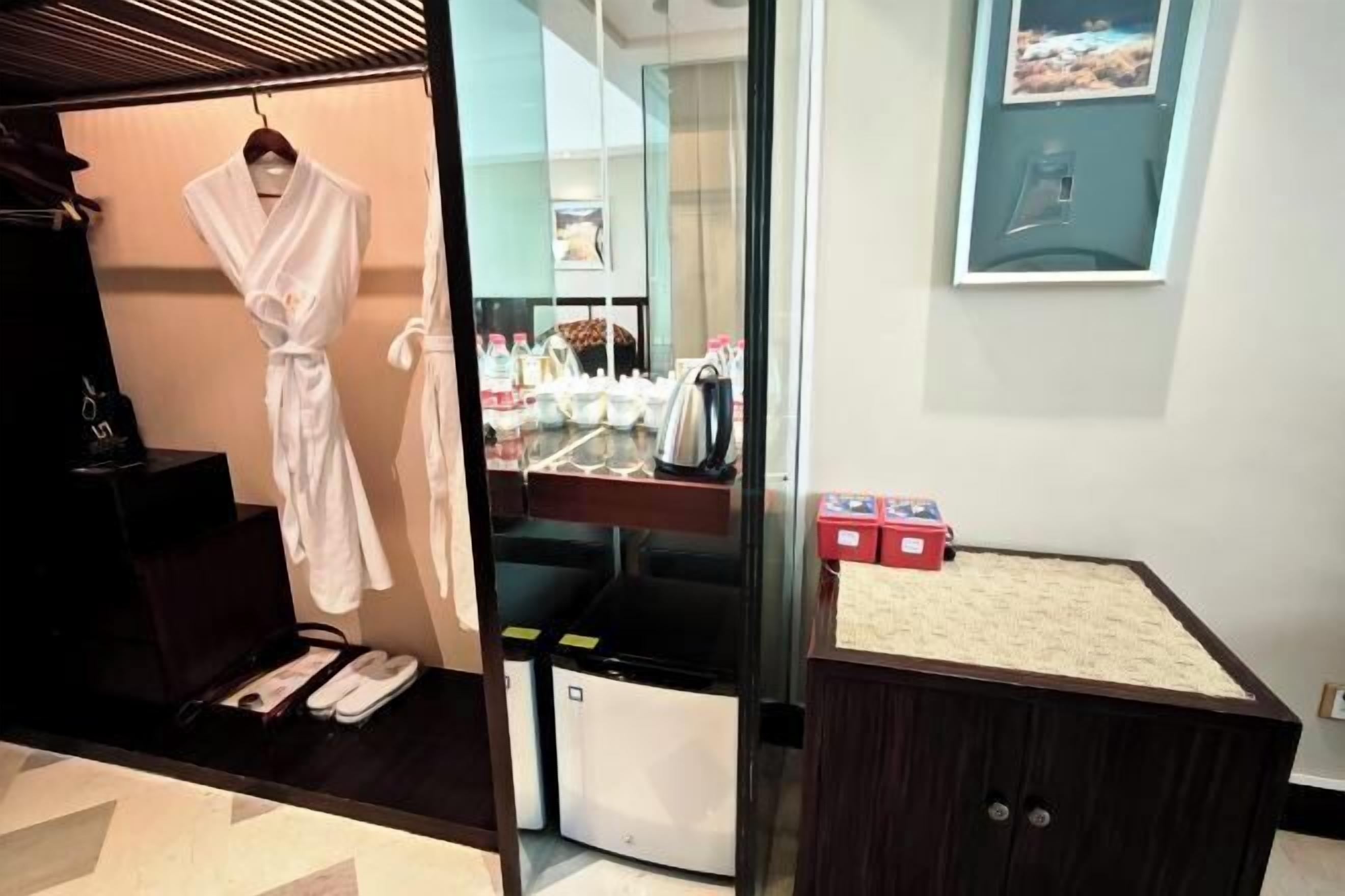 A hotel room with a robe hanging, a sink with toiletries, and a small cabinet.