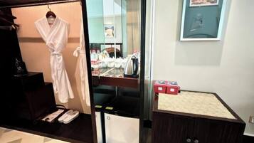 A hotel room with a robe hanging, a sink with toiletries, and a small cabinet.