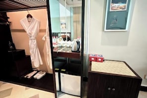 A hotel room with a robe hanging, a sink with toiletries, and a small cabinet. - Seercuo International Hotel (Songpan)