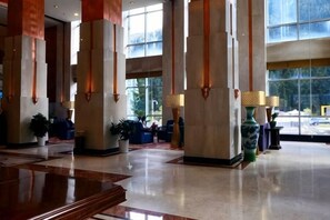 A spacious lobby with high ceilings, large windows, and a polished floor.