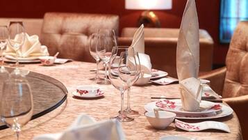 A dining table set with plates, glasses, and folded napkins in a room with a sofa and a lamp.
