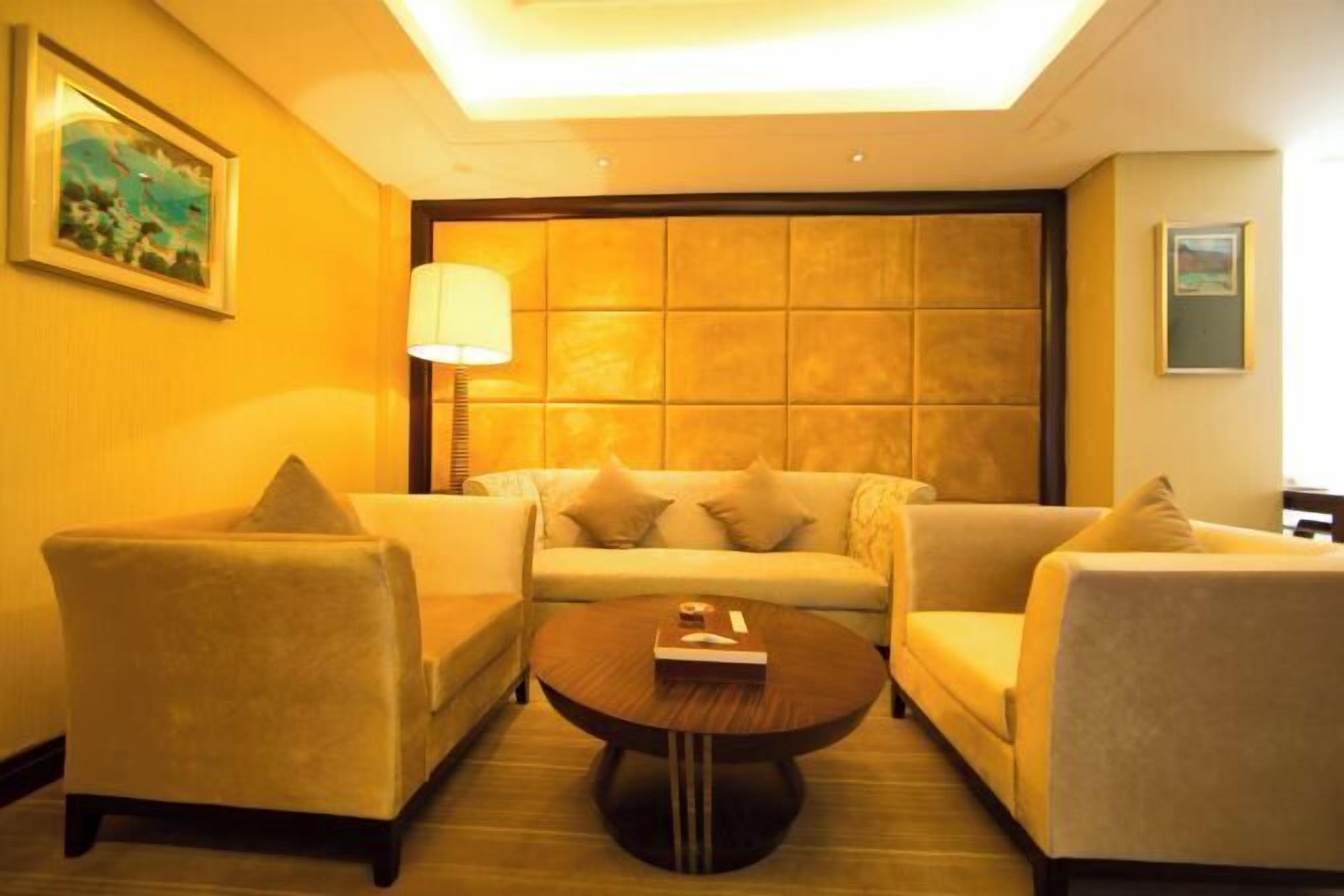 A hotel room with a sofa set, a coffee table, and a lamp.
