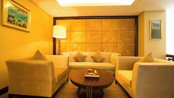 A hotel room with a sofa set, a coffee table, and a lamp.