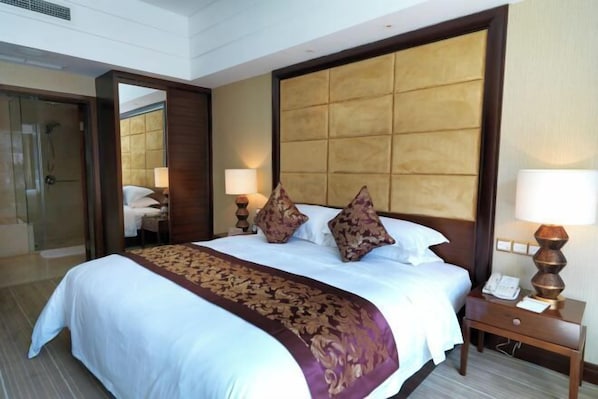 A hotel room with a large bed, two bedside lamps, and a wooden headboard.