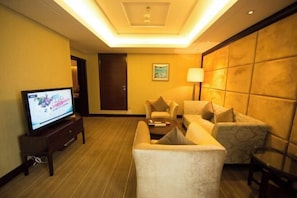 Habitació d'hotel amb televisió, dos sofàs, una làmpada i una porta.