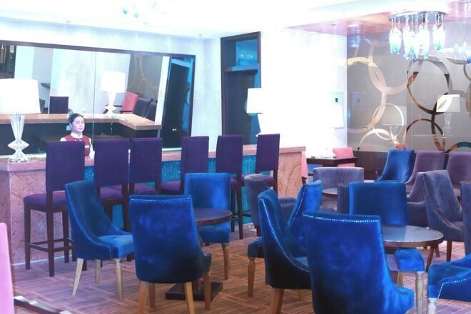 Un vestíbulo de hotel con varias zonas de estar, un mostrador de recepción y un espejo grande.