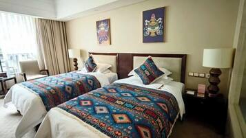 A hotel room with two beds, a desk, and a chair.