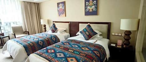 A hotel room with two beds, a desk, and a chair.