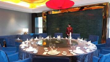 A conference room with a round table, blue chairs, and a person standing at the table.