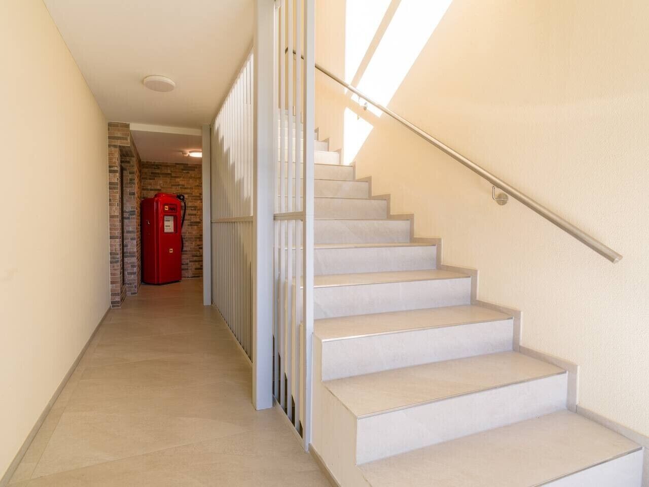 A staircase with a handrail, a red mailbox, and a brick wall in the background.