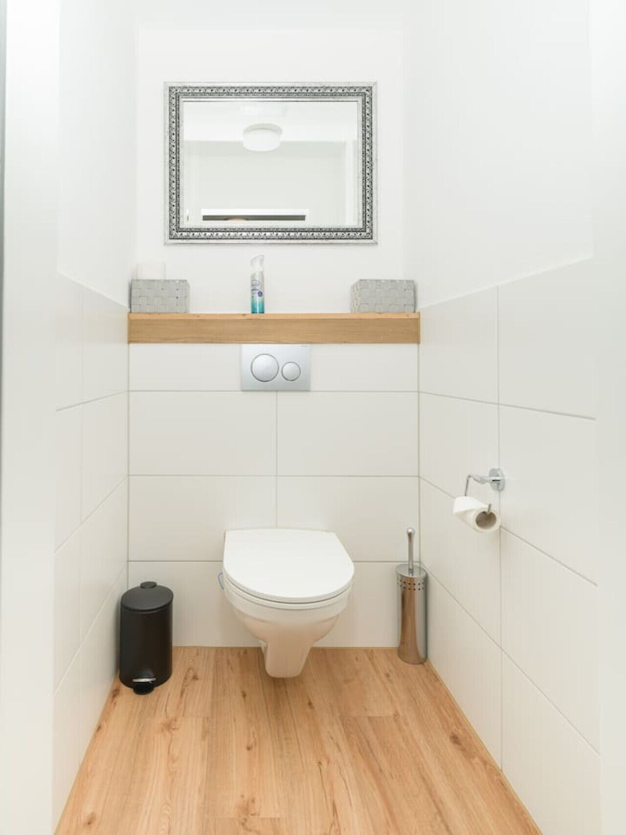 Ein kleines, modernes Badezimmer mit Toilette, einem Händetrockner und einem Mülleimer.