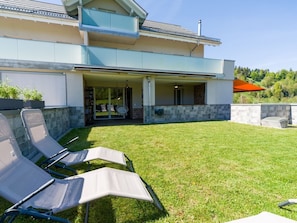A modern two-story building with a covered patio area and a grassy lawn.