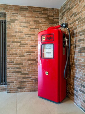 A red Agip fuel pump against a brick wall.