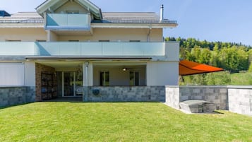 A modern two-story house with a covered patio and a stone wall.