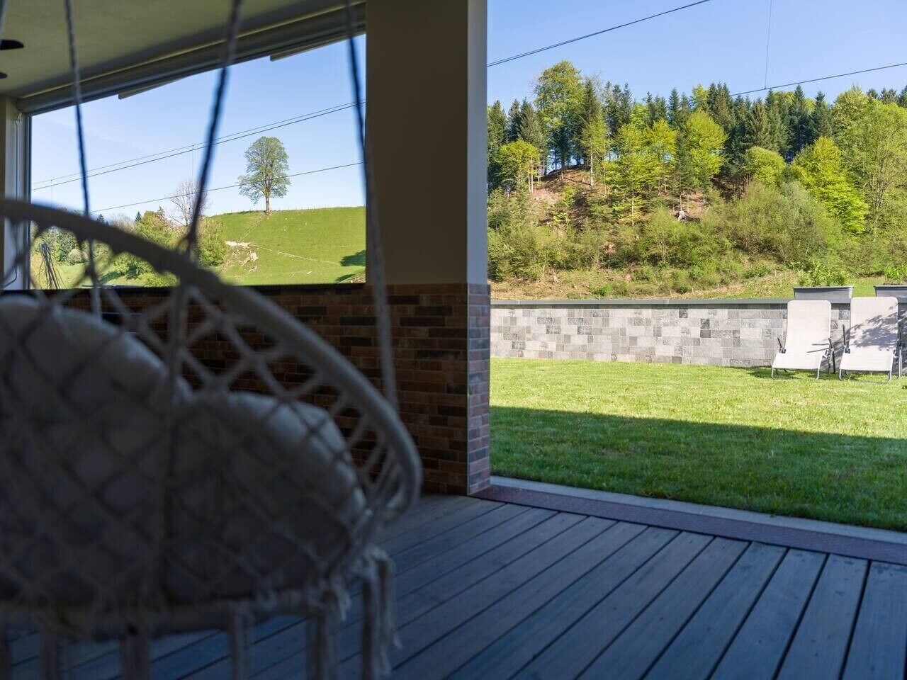 A covered outdoor area with a view of a grassy field and trees.