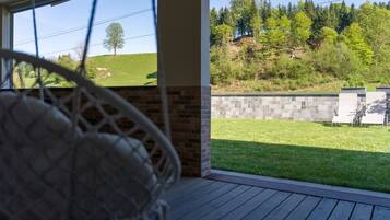 A covered outdoor area with a view of a grassy field and trees.