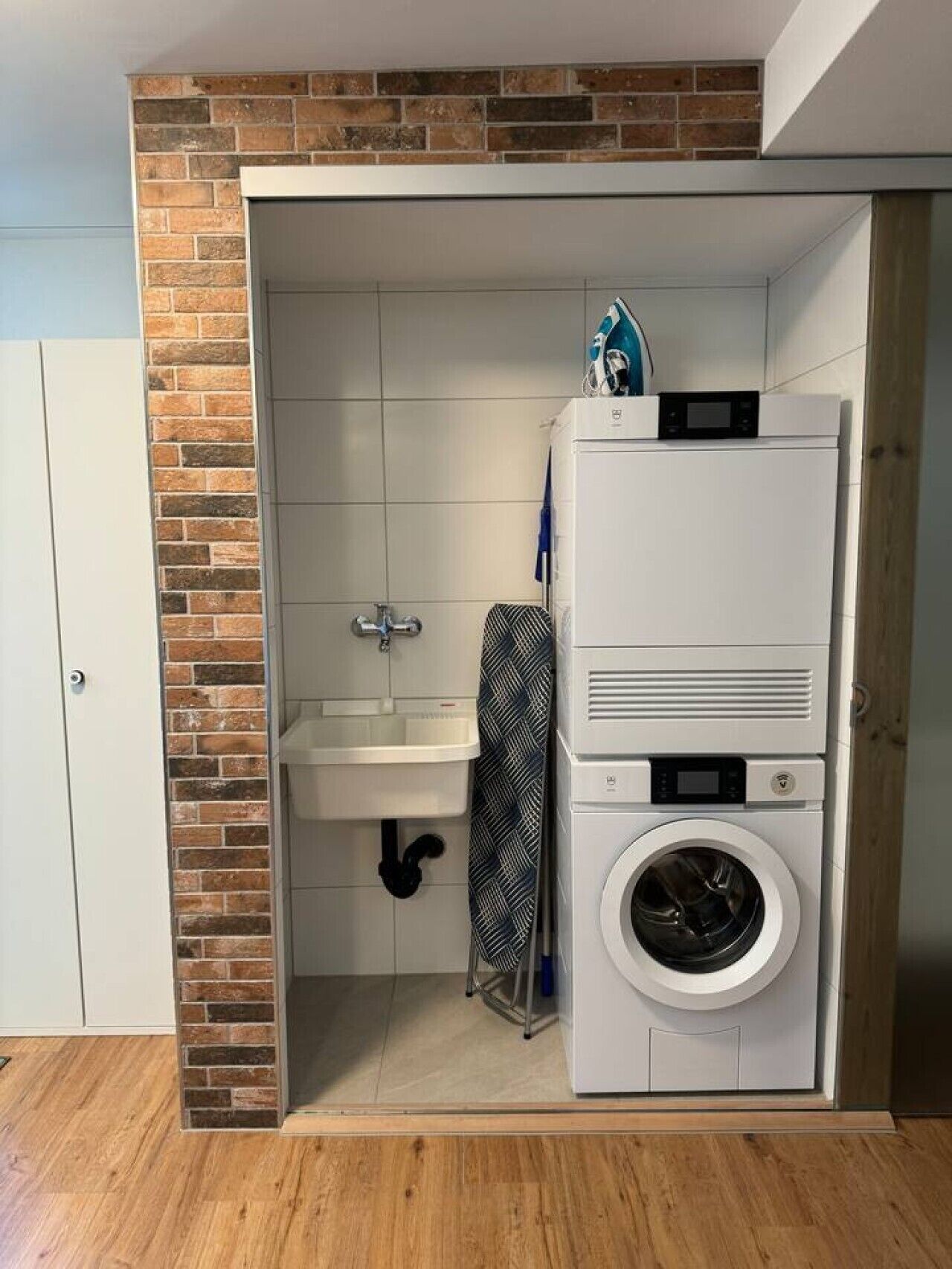 Une petite buanderie équipée d’un lave-linge, d’un sèche-linge et d’un évier.