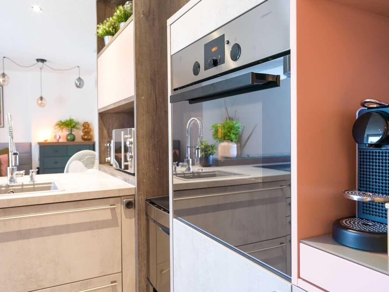 Een moderne keuken met een inbouwoven, een koffieapparaat en een spoelbak.
