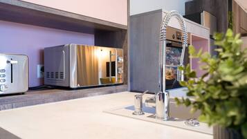 Eine moderne Küche mit einem Edelstahlkühlschrank, einem Toaster und einem Waschbecken mit Armatur.