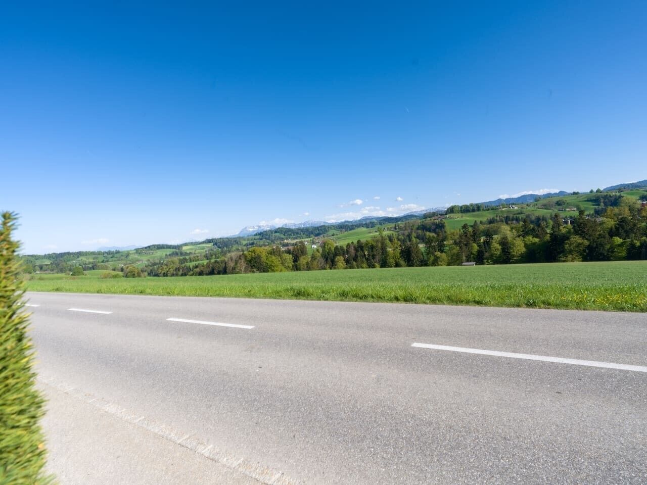Una carretera despejada con paisaje verde y colinas al fondo.
