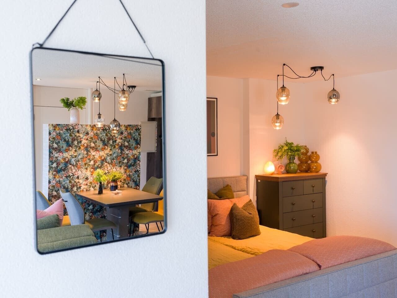 Una habitación con zona de comedor, cama y cómoda.