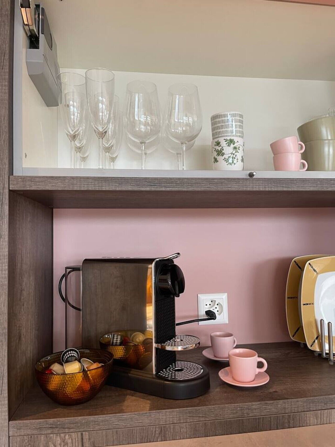 Eine Küchenarbeitsplatte mit einer Kaffeemaschine, einer Schüssel und einem Satz pinkfarbener Tassen.