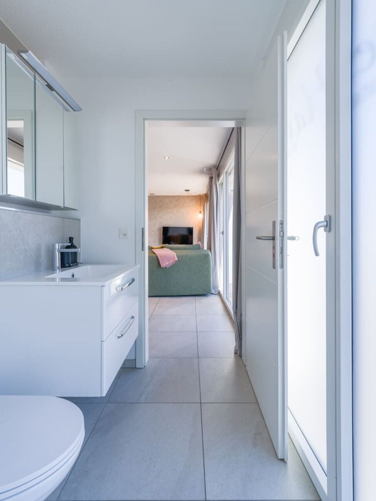 Ein modernes Badezimmer mit Toilette, Waschbecken und Spiegel.