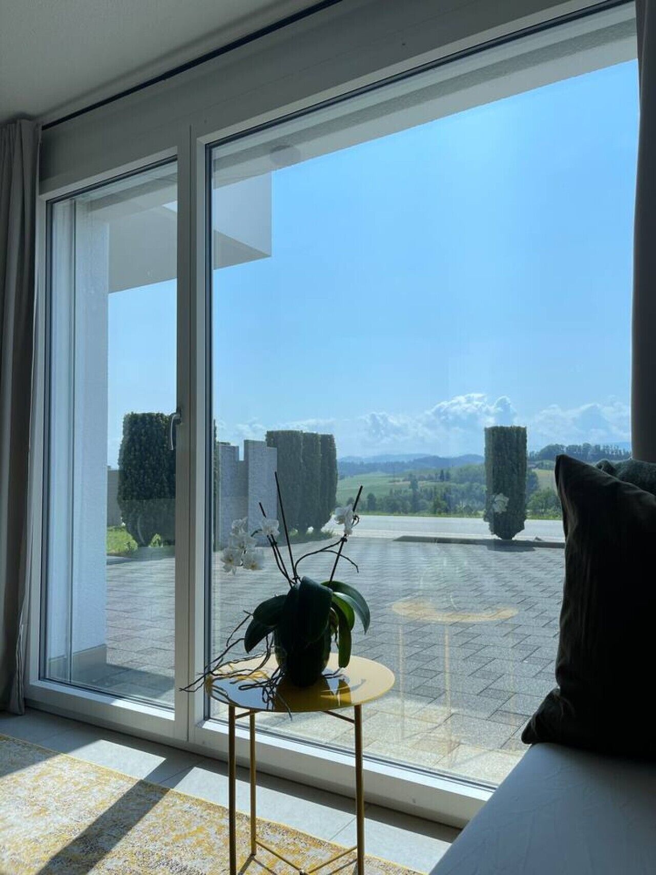 Una stanza con un'ampia porta-finestra scorrevole che dà su un cortile con vista su montagne e alberi.