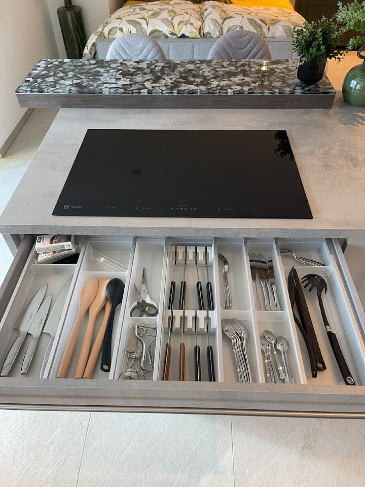 Een moderne keuken met een geïntegreerde inductiekookplaat en een uitschuifbare lade-organizer voor keukengerei.
