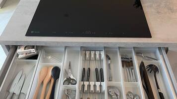 Een moderne keuken met een geïntegreerde inductiekookplaat en een uitschuifbare lade-organizer voor keukengerei.