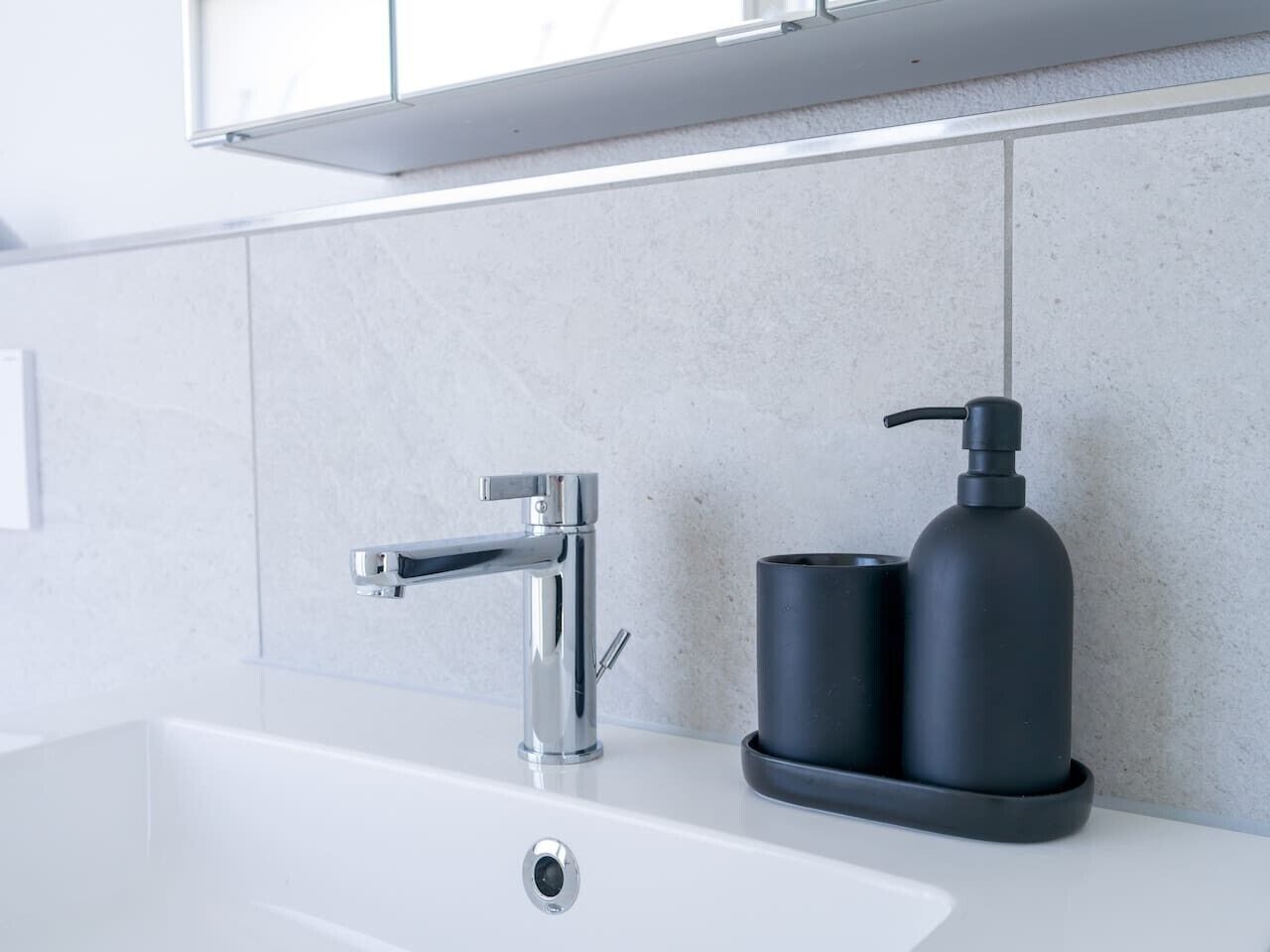 Une salle de bain moderne avec un robinet chromé, un distributeur de savon noir et un lavabo blanc.