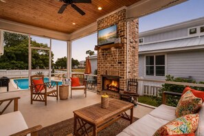 An outdoor patio with a brick fireplace, seating, and a pool. - Heated Saltwater Pool - 3BR Home - Gulfport (Gulfport)