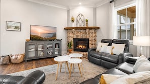 Ein Wohnzimmer mit Kamin, Ledersofa und Fernseher.