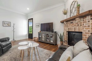 A living room with a fireplace, a television, a sofa, and a coffee table. - Heated Saltwater Pool - 3BR Home - Gulfport (Gulfport)