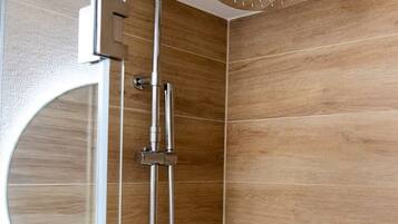Une douche équipée d’un pommeau de douche à effet pluie, d’un pommeau de douche à main et d’un flexible de douche à main.